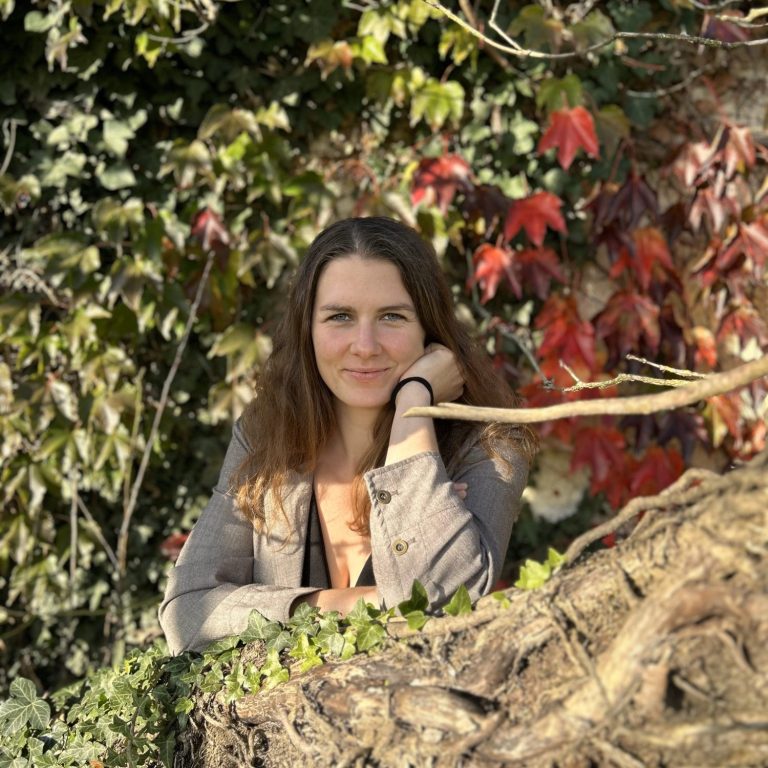 Dieses Bild zeigt eine Frau im fliederfarbenen Pulli, wie sie entspannt und lächelnd an einem 100% rein ätherischem Öl schnuppert, das Zitronenöl beinhaltet.